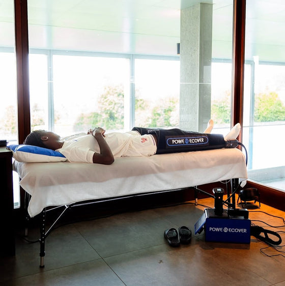 Séance de cryothérapie compressive du genou sur une table de soin, froid et compression appliqués après une intervention